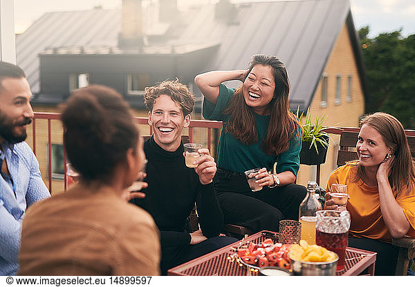 Fröhliche Freunde unterhalten sich bei geselligem Beisammensein auf der Terrasse