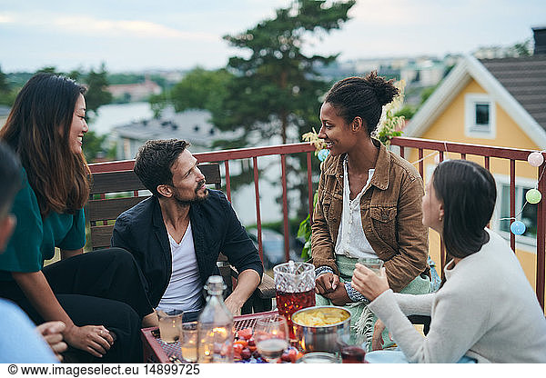 Fröhliche Freunde unterhalten sich beim geselligen Beisammensein auf der Terrasse