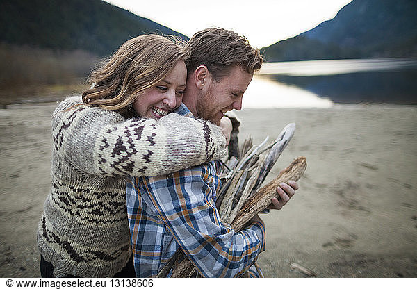 Fröhliche Freundin umarmt im Silver Lake Provincial Park ihren Freund  der Brennholz trägt