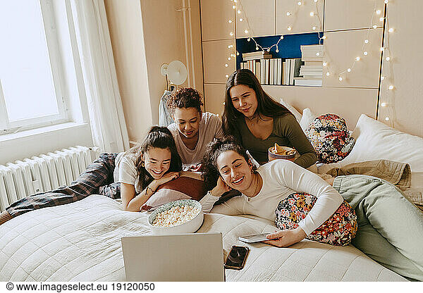 Fröhliche  gemischtrassige Freunde  die zu Hause gemeinsam einen Film auf dem Laptop ansehen