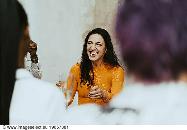 Fröhliche Geschäftsfrau lacht bei der Interaktion mit Kollegen während einer Veranstaltung im Kongresszentrum
