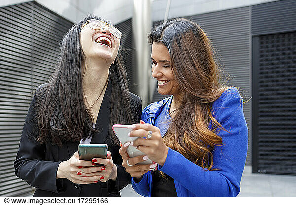 Fröhliche Geschäftsfrauen mit Mobiltelefonen