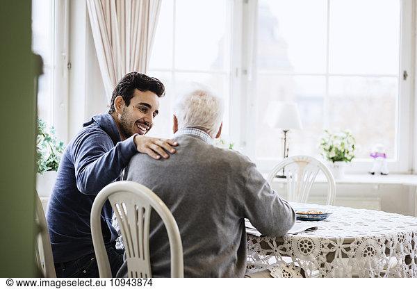 Fröhliche Hausmeisterin kommuniziert mit Senioren im Pflegeheim