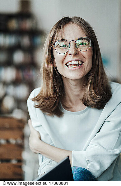 Fröhliche junge Geschäftsfrau mit braunen Haaren sitzt in einem Café