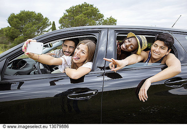 Fröhliche männliche und weibliche Freunde  die im Auto sitzen
