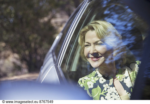 Fröhliche Seniorin schaut auf das Autofenster