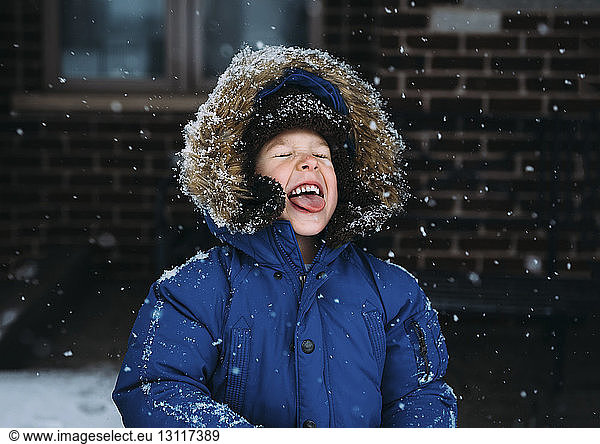 Fröhlicher Junge geniesst Schneefall
