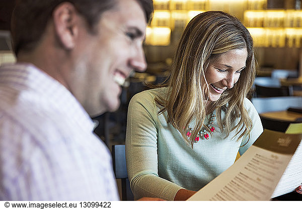 Fröhliches Paar mittlerer Erwachsener liest Speisekarte im Restaurant