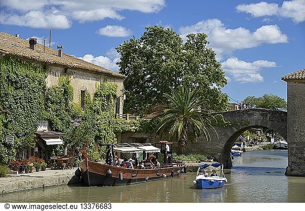 France  Aude  Saint Nazaire d'Aude  Canal du Midi listed as World Heritage by UNESCO  Port of Somail  boats of tourism in front of a building in murx covered with Virginia creeper with a background bridge