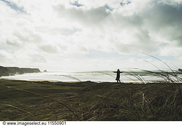 France  Bretagne  Finistere  Crozon peninsula  woman standing at the coast with outstretched arms