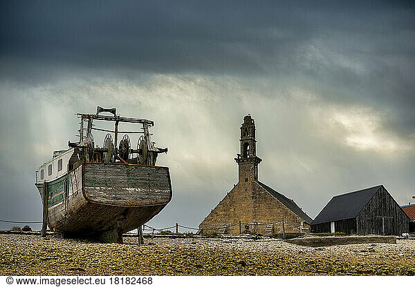 France  Brittany  Camaret-sur-Mer  Trawler in ship cemetery with Chapelle Notre-Dame-De-Rocamadour in background