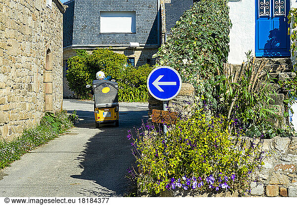 France  Brittany  Saint-Pierre-Quiberon  Road sign in front of town alley with electric car moving in background