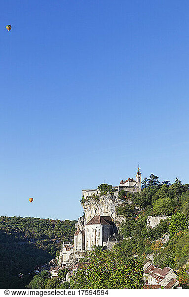 France  Lot  Rocamadour  Clear sky over cliffside town with hot air balloons in background