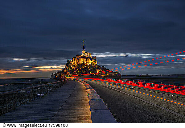 France  Normandy  Vehicle light trails stretching along bridge connecting Mont-Saint-Michel island at dusk