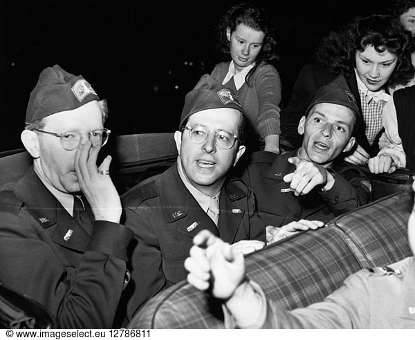 FRANK SINATRA (1915-1998). American singer and actor. Sinatra (right)  actor and comedian Phil Silvers (center)  and composer and pianist Saul Chaplin  on their way to perform overseas with the USO  photographed outside a restaurant in New York City as young bobby-soxers swarm around their convertible  29 May 1945.
