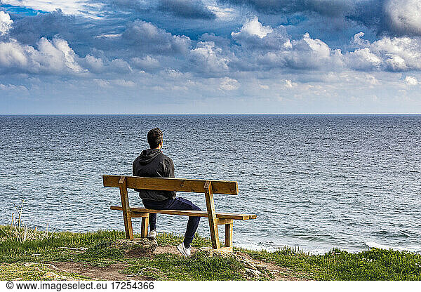 Frankreich  Bretagne  Finistere sud  Rückansicht eines Mannes auf einer Bank mit Blick aufs Meer