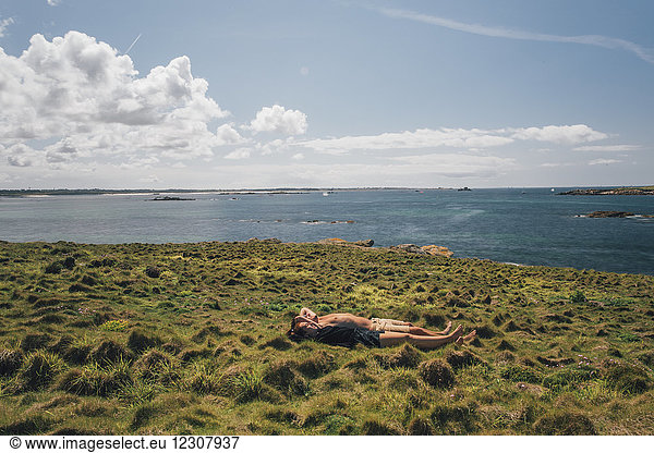 Frankreich  Bretagne  Landeda  Dunes de Sainte-Marguerite  junges Paar im Gras an der Küste liegend