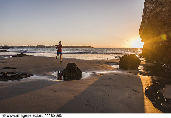 Frankreich Halbinsel Crozon Jogger am Strand bei Sonnenuntergang