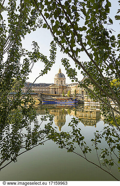 Frankreich  Ile-de-France  Paris  Institut de France  das sich in der Seine spiegelt  mit Zweigen im Vordergrund