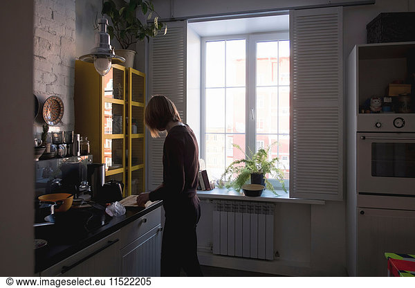 Frau am Küchentisch beim Zubereiten von Essen