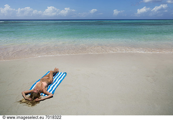 Frau auf Handtuch am Strand liegend