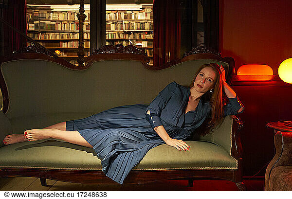 Frau auf Sofa in Bibliothek liegend