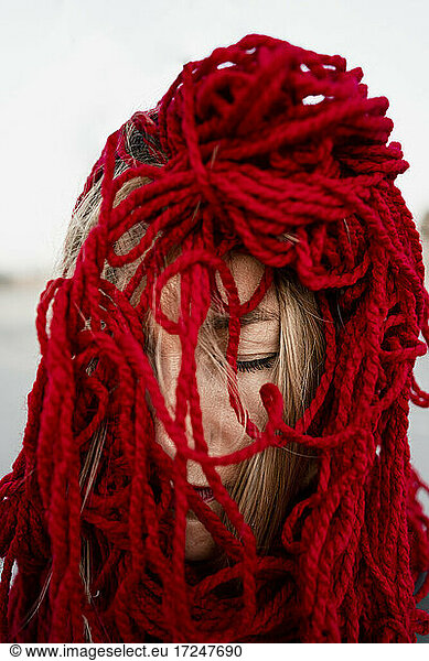 Frau bedeckt Gesicht mit rotem Faden