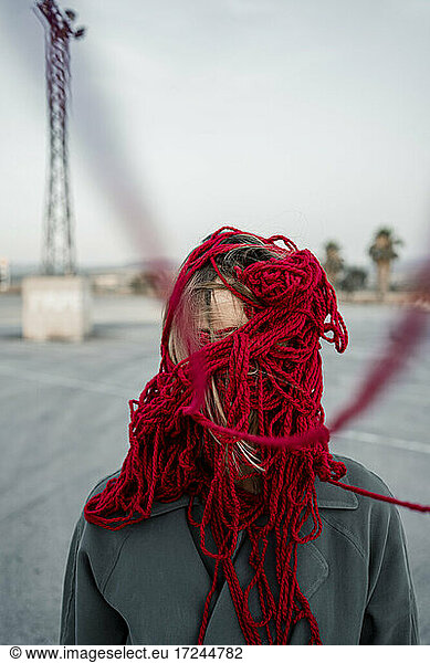 Frau bedeckt Gesicht mit rotem Faden auf der Straße