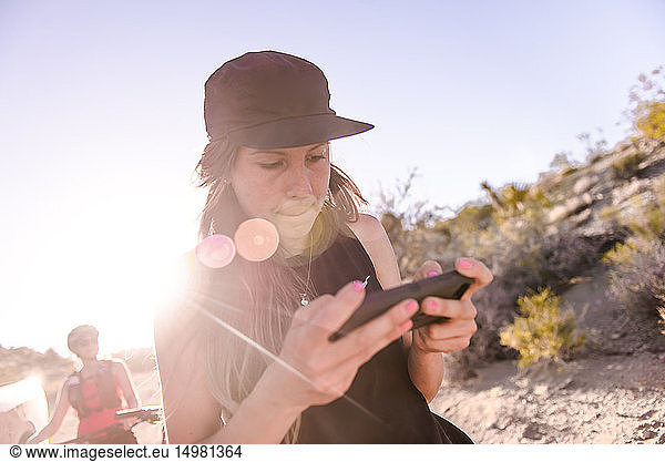 Frau bedient Drohne (unbemanntes Luftfahrzeug) mit Smartphone auf ländlichem Feldweg
