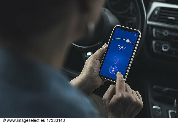 Frau bedient Temperatur über Smartphone im Auto