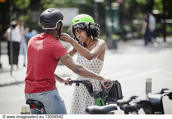 Frau befestigt Fahrradhelm eines Mannes