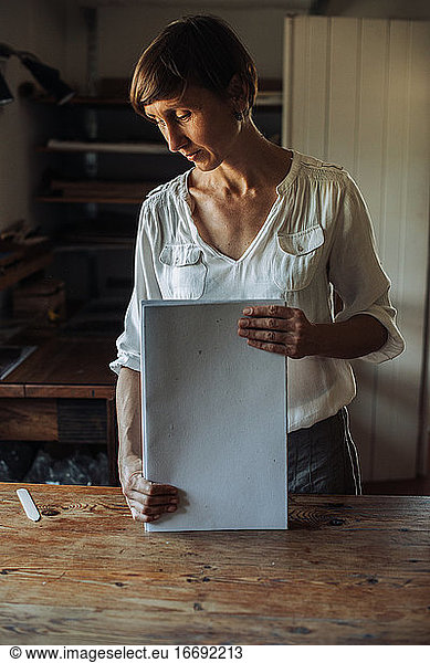 Frau bei der Handhabung eines Stapels von Papierbögen  Prozess der Herstellung eines handgefertigten Buches