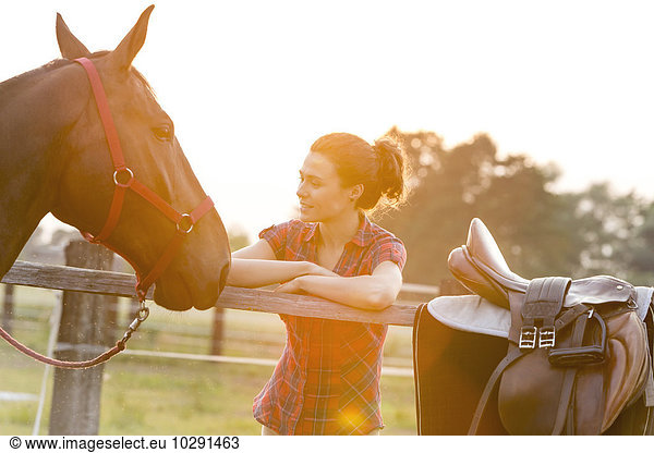 Frau beim Anblick eines Pferdes am Weidezaun