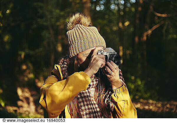 Frau beim Fotografieren mit Kamera im Wald