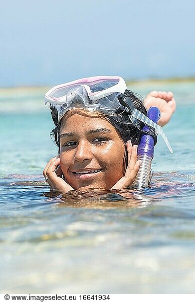 Frau beim Schnorcheln mit Maske und Schnorchelschlauch schaut in die Kamera. Körper unter Wasser. Entspannen im tropischen Sommerurlaub. Karibik Reiseziel.