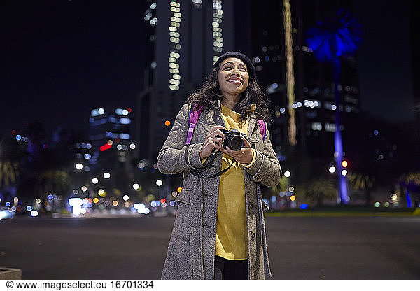 Frau beim Sightseeing und Fotografieren auf der Straße bei Nacht