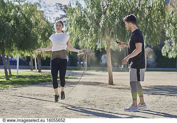Frau beim Training mit Trainer  der im Park Seil springt