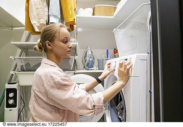 Frau benutzt Waschmaschine im Hauswirtschaftsraum