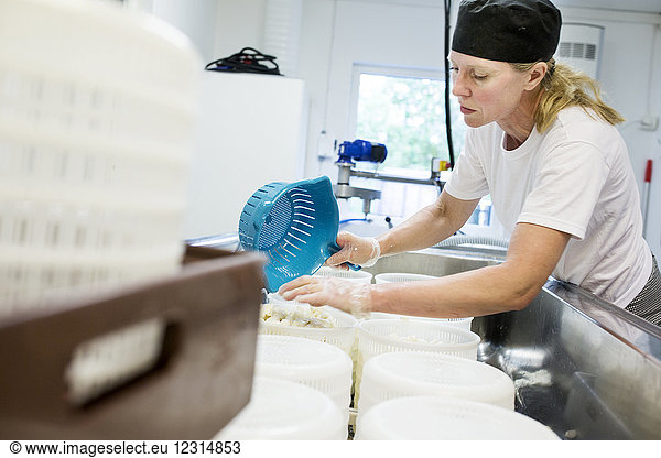 Frau bereitet Hüttenkäse in einer Großküche zu
