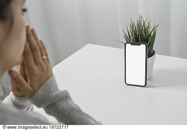 Frau betet mit Smartphone zu Hause