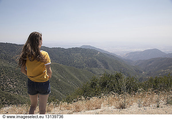 Frau betrachtet Aussicht  während sie gegen Berge und Himmel steht