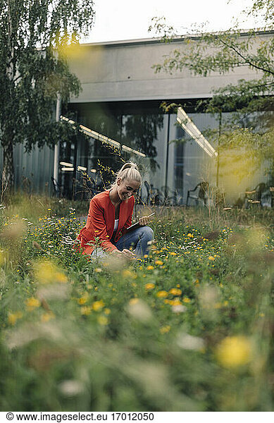 Frau betrachtet Blumen im Firmengarten