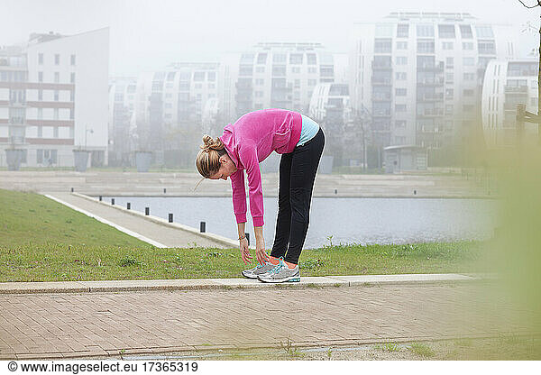 Frau beugt sich beim Sport im Park