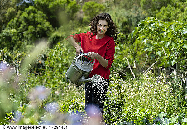 Frau bewässert Pflanzen im Garten