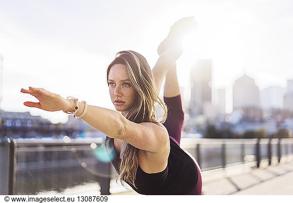 Frau übt Yoga-Position in der Stadt bei klarem Himmel