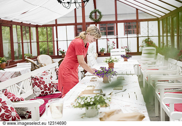 Frau deckt Tisch im Wintergarten