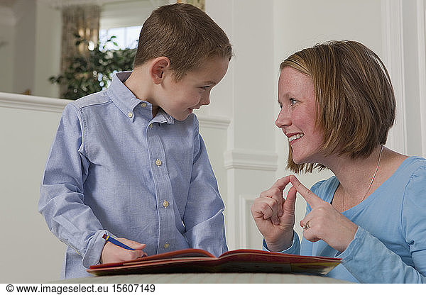 Frau  die das Wort Word in amerikanischer Zeichensprache gebärdet  während sie ihren Sohn unterrichtet
