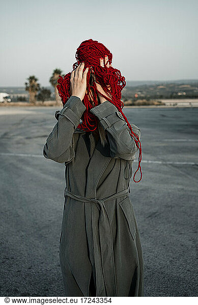 Frau  die ihr Gesicht mit einem Faden bedeckt  steht auf der Straße