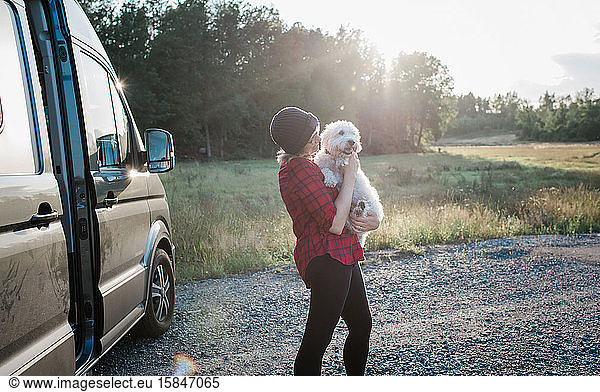 Frau  die im Sommer beim Camping in einem Wohnmobil ihren Hund hält