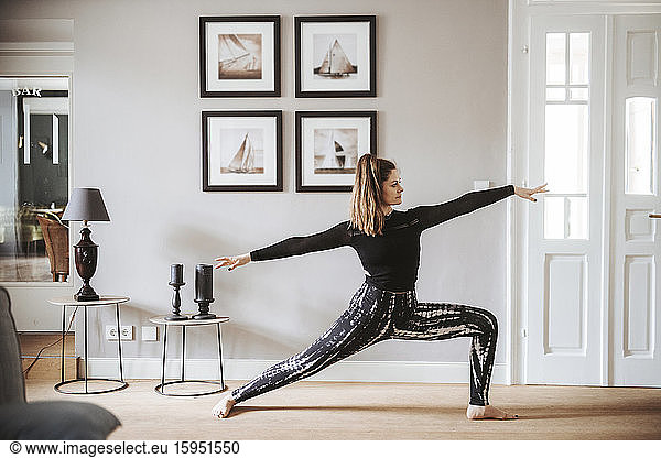 Frau  die zu Hause Yoga praktiziert  Krieger-Pose